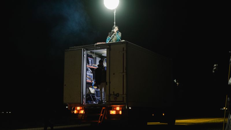 A film crew at night using a truck equipped with powerful lighting for shooting.