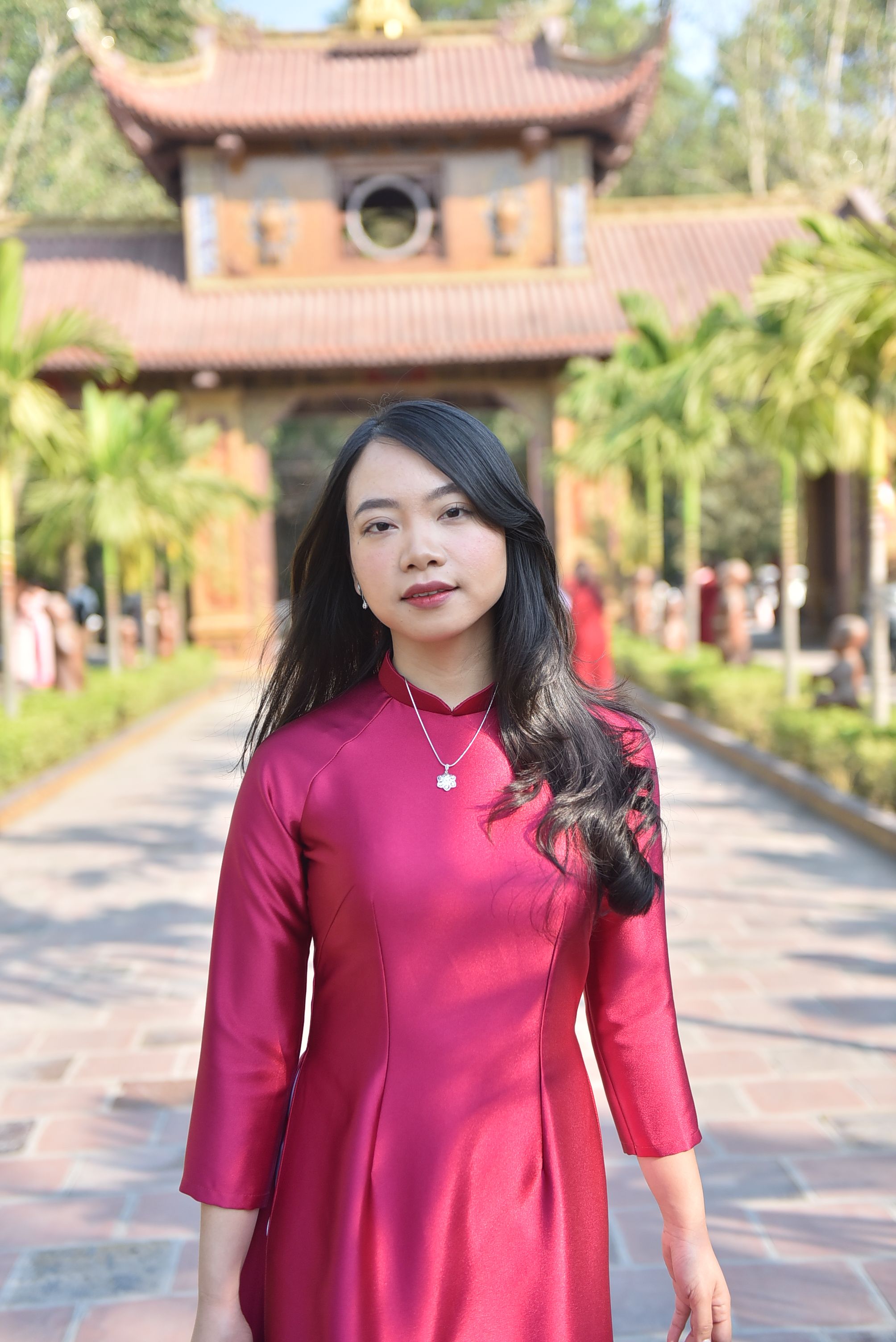 Portrait of a woman in a red dress at a traditional Asian landmark.
