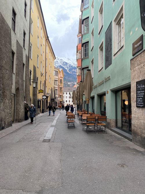 Free View of a narrow European street with colorful buildings and distant mountains. Stock Photo