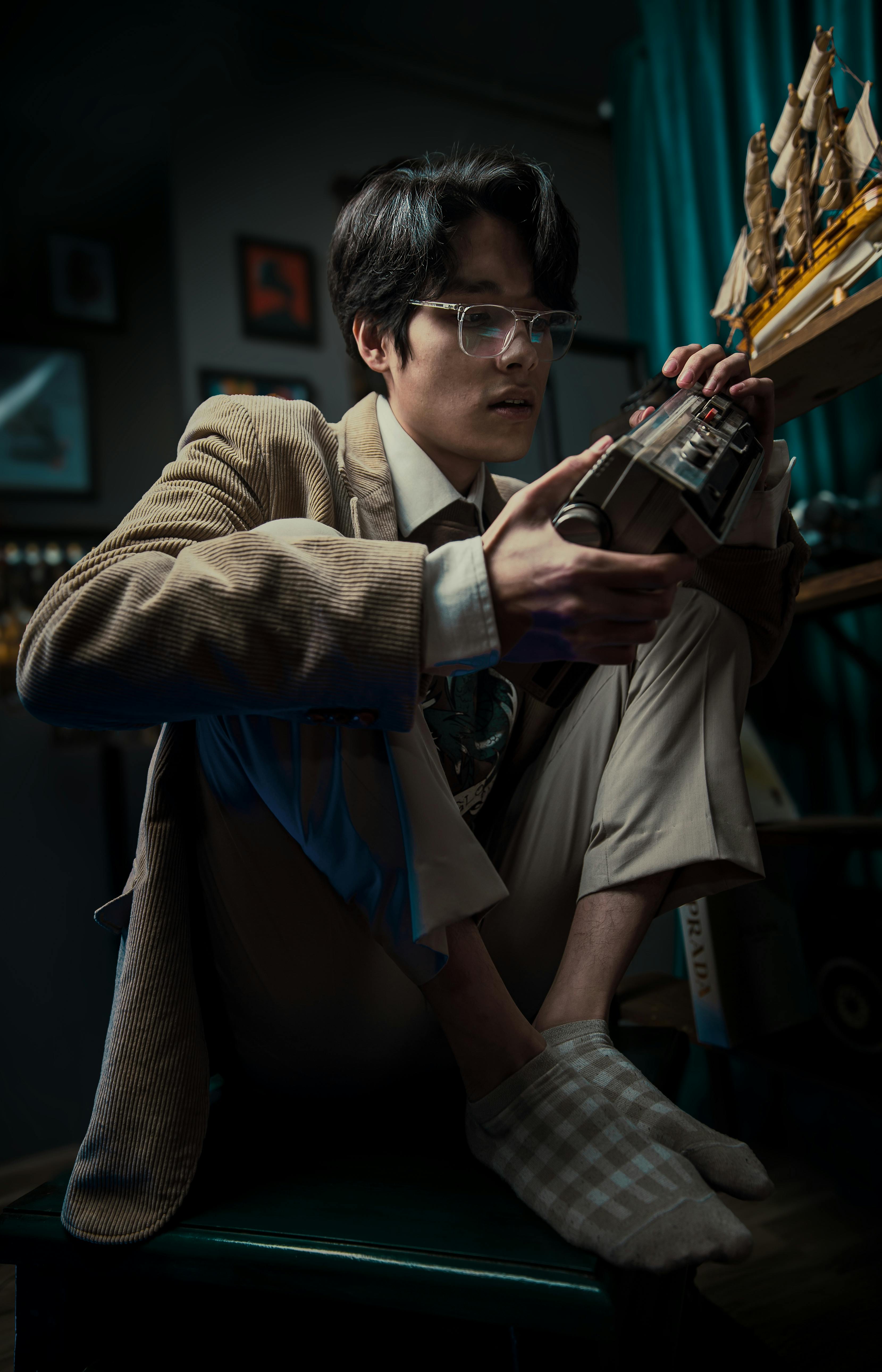 Gratuit Jeune adulte jouant à une console de jeux vidéo vintage dans une pièce de style rétro avec exposition de maquettes de bateaux. Photos