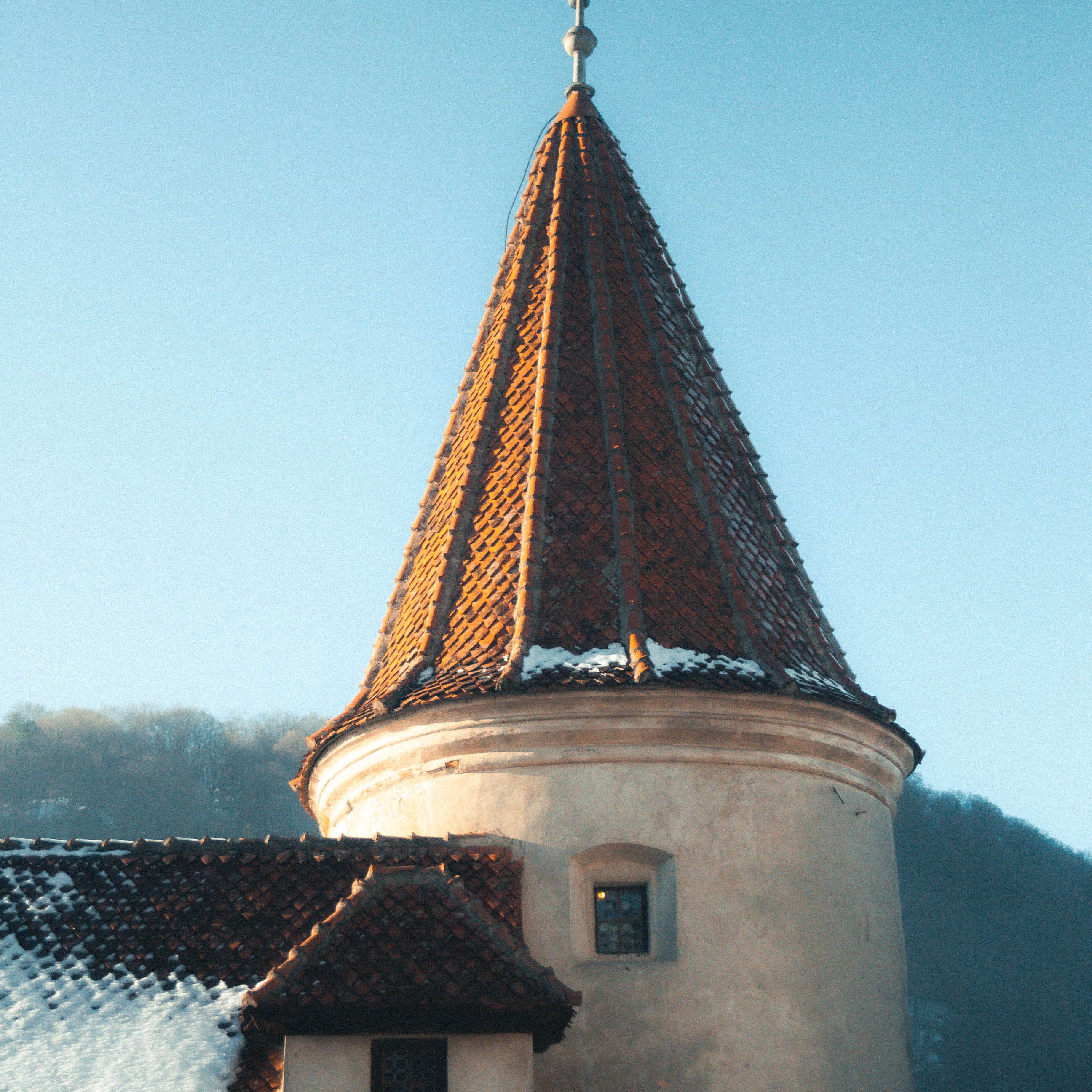 Close-up of a snowy turret of Bran Castle in Romania, capturing winter beauty.