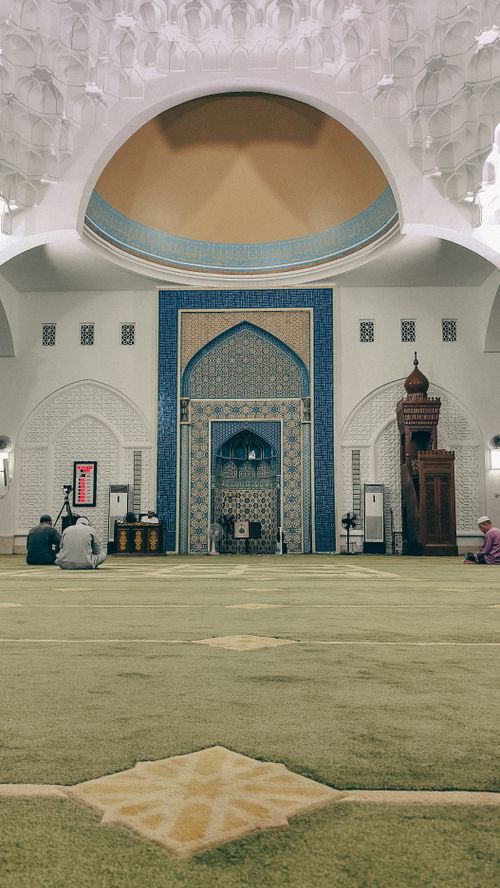 Free Elegant mosque interior with worshippers, showcasing intricate Islamic architecture and peaceful ambiance. Stock Photo