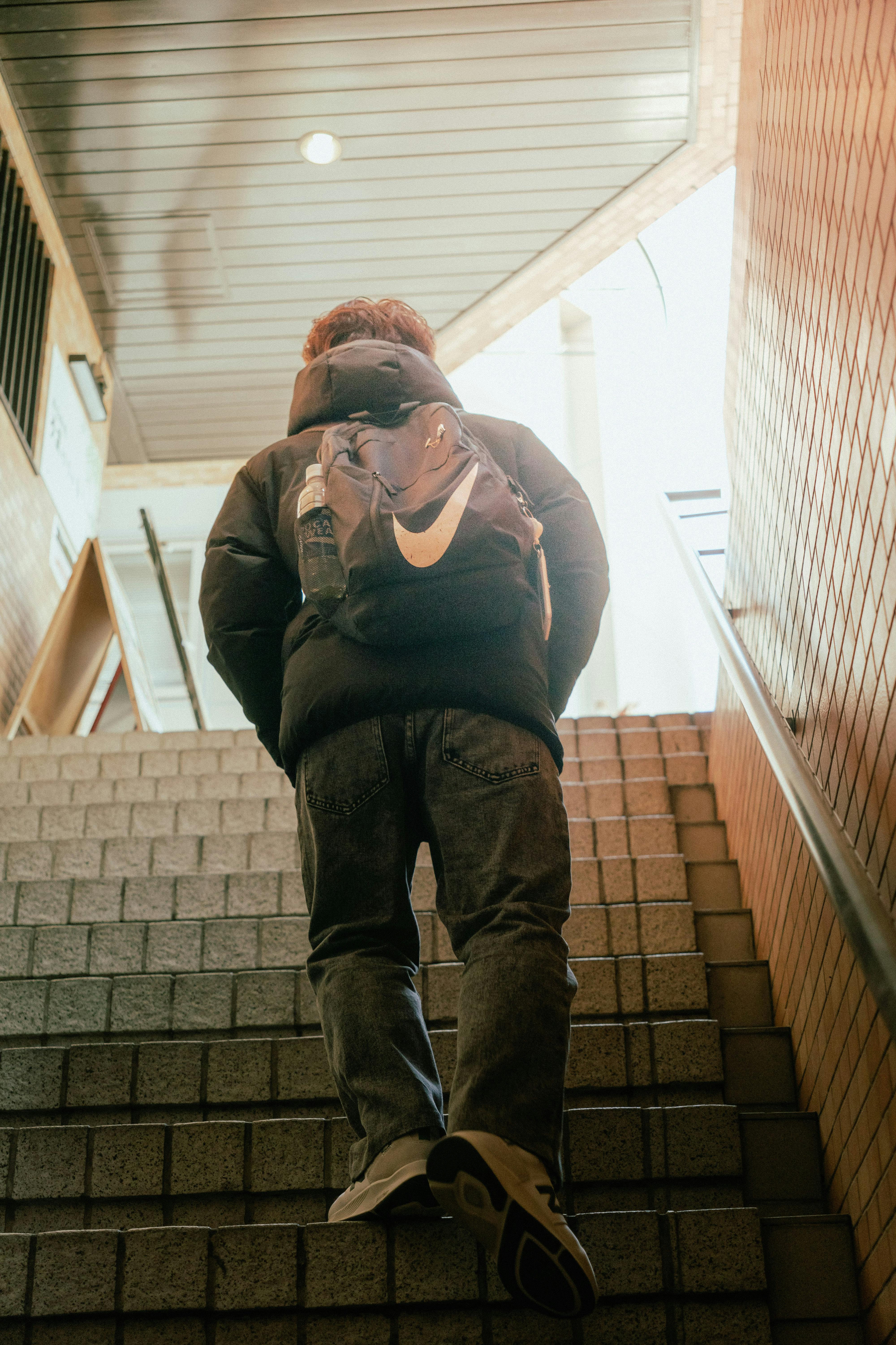 Tânăr urcând scările cu un rucsac