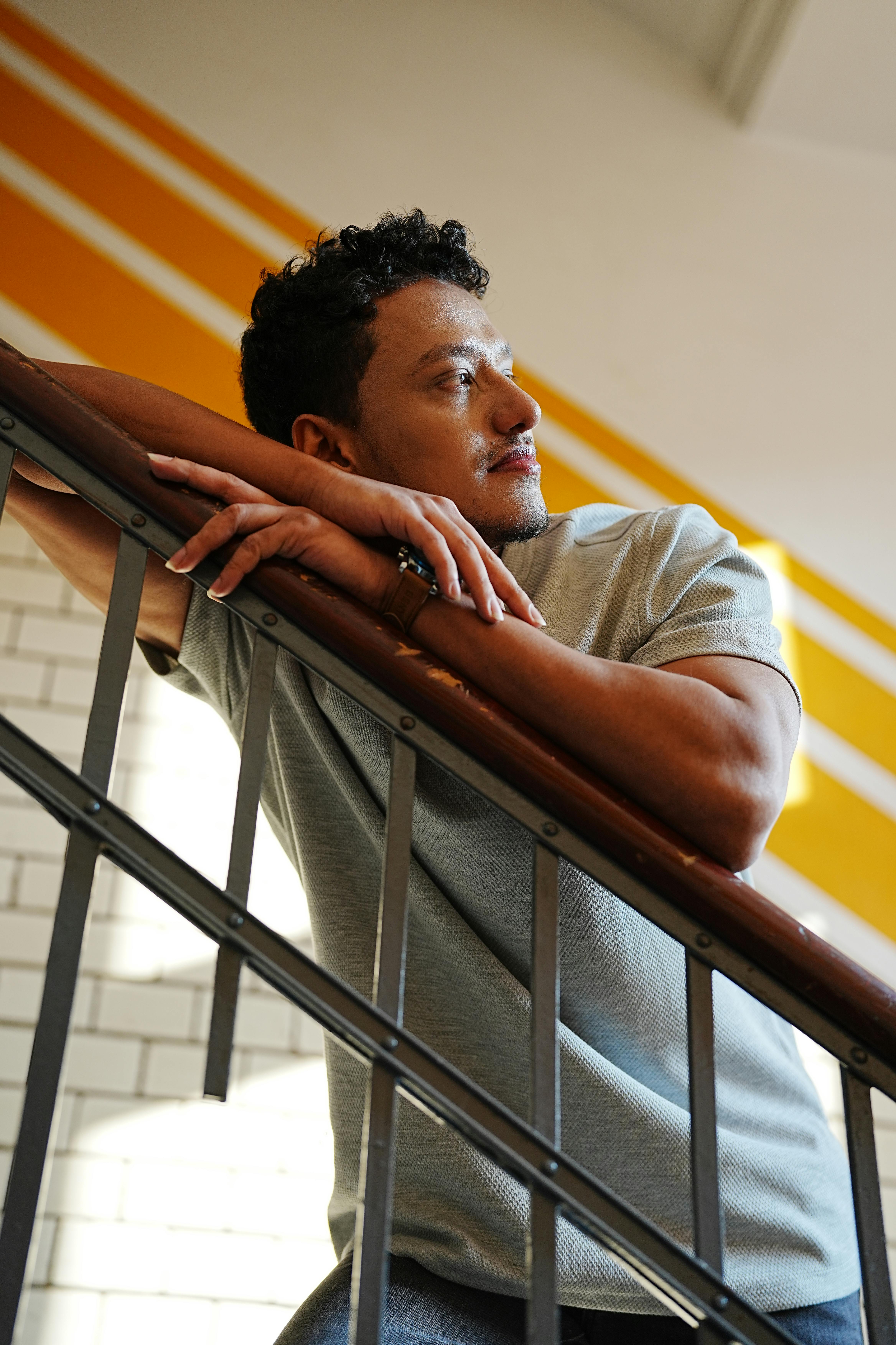 Portrait of a contemplative man leaning on a staircase indoors, captured in Berlin.