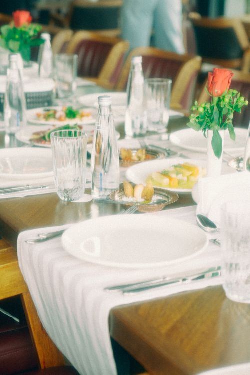 Free Charming dining table with elegant setup featuring a red rose centerpiece, perfect for special occasions. Stock Photo