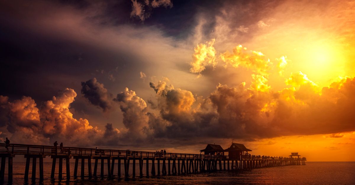 A breathtaking sunset over a scenic ocean pier, capturing vibrant clouds and silhouettes.