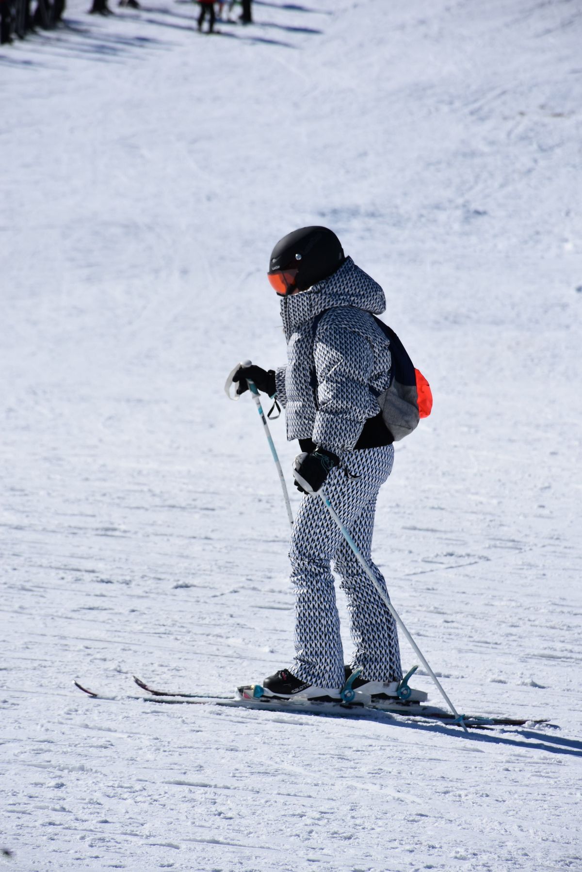 Snowboarder riding through bright alpine snow with a steep mountain backdrop.