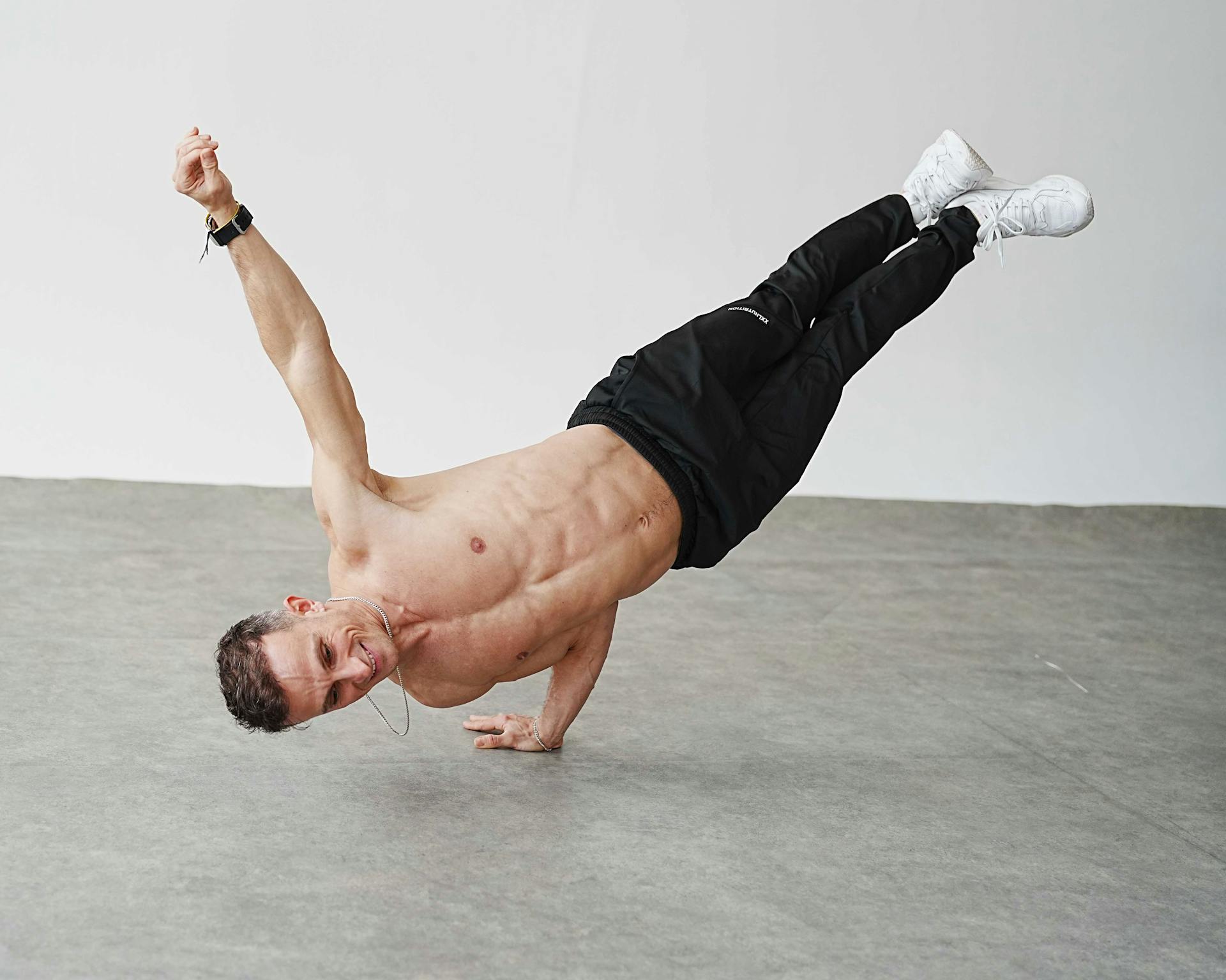 Energetic man performing a one-arm handstand in a Berlin studio. Capturing movement and strength.