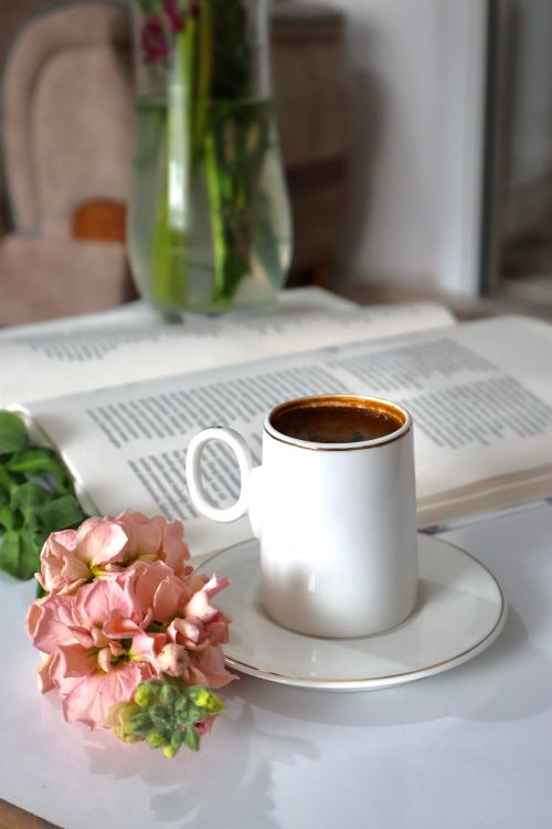 Free A serene scene of coffee, flowers, and an open book for a relaxing mood. Stock Photo