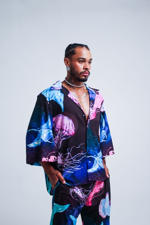 Free Fashionable man in colorful jellyfish print attire posing confidently against a plain backdrop. Stock Photo