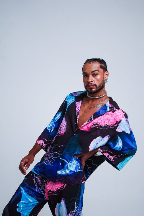 Free A stylish young man poses in colorful, artistic clothing on a neutral background. Stock Photo