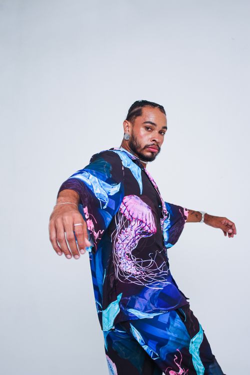 Free Confident man posing in colorful artistic clothing with abstract design. Ideal for fashion and lifestyle themes. Stock Photo