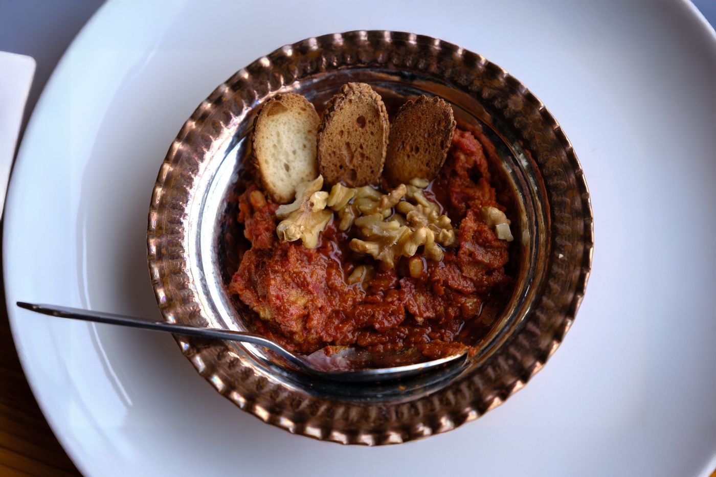 Delicious Turkish muhammara dip with walnuts and bread slices served in a rustic bowl.
