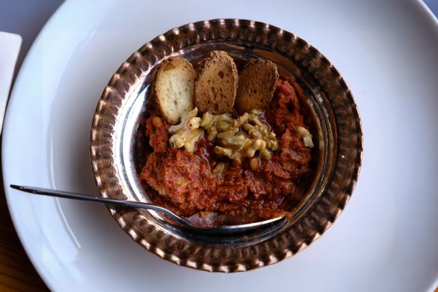 Delicious Turkish muhammara dip with walnuts and bread slices served in a rustic bowl.