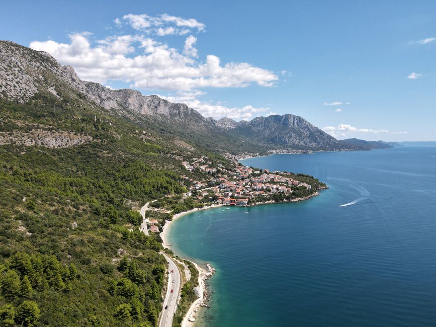 Scenic aerial shot of Podaca, Croatia with coastal mountains and clear blue sea.