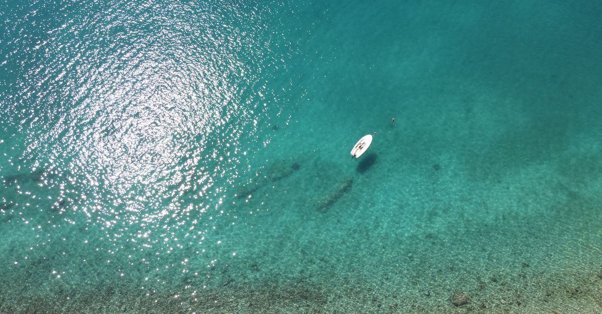 Serene aerial view of a paddleboarder floating on crystal-clear Adriatic waters near Podaca, Croatia.