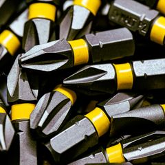 Close-up of a heap of steel screwdriver bits with bright yellow bands