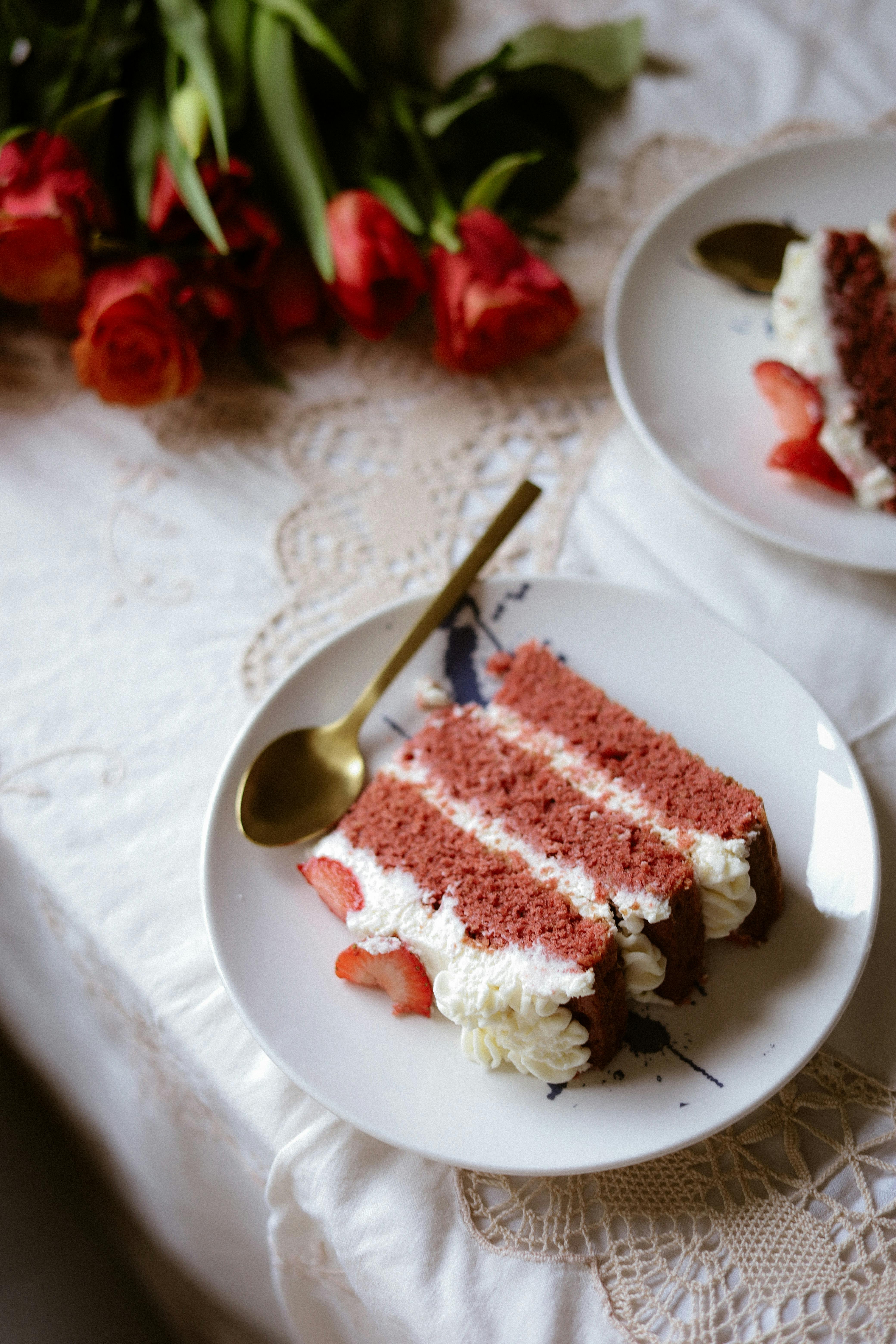 A slice of red velvet cake with cream cheese frosting on a plate, perfect dessert setting.