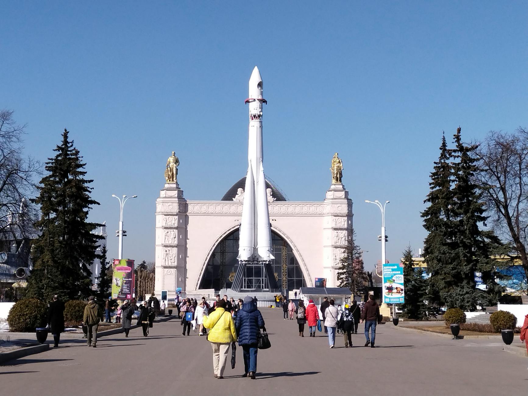 Visitors exploring VDNKh with Vostok rocket exhibit in Moscow.