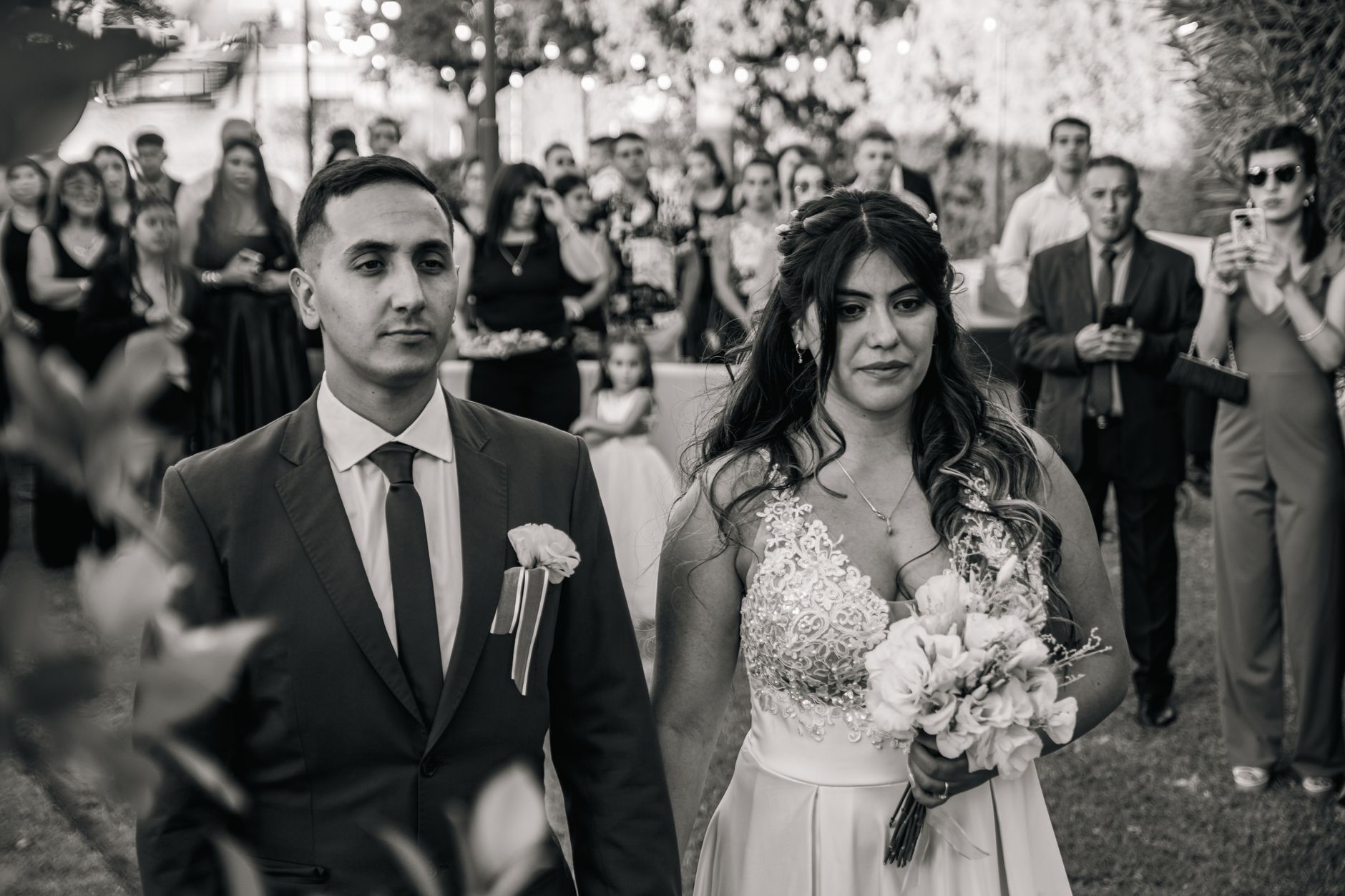 Bride and groom during an outdoor wedding ceremony surrounded by guests.