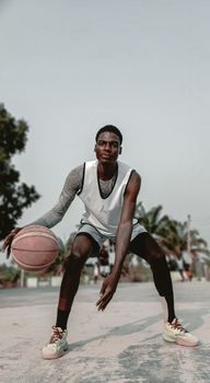 A young male basketball player dribbling on an outdoor court in Moro, Nigeria.