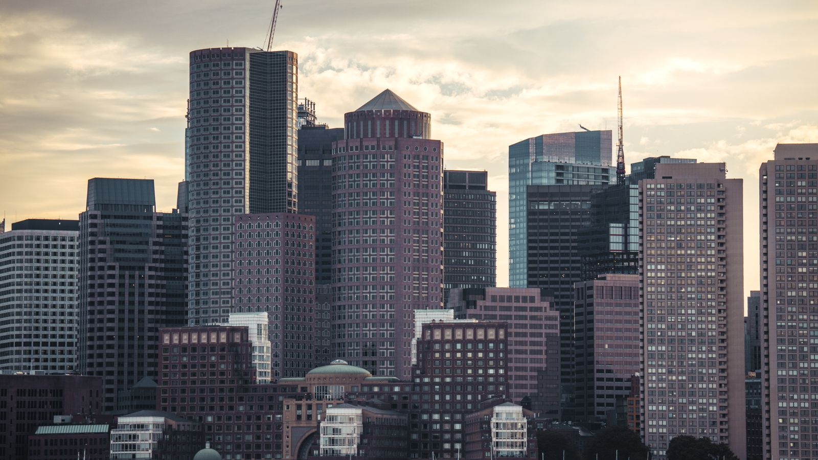 Boston skyline at dusk with high-rise buildings along the waterfront, no people in the frame, a real stock photo that sets the scene for Love Is Blind Season 11, the first season filmed with singles from Boston