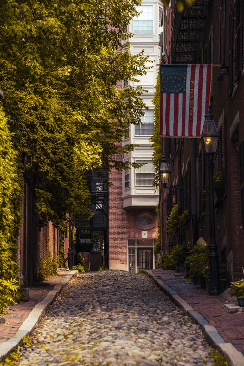 Free Charming historic street in Boston with cobblestone path and American flag. Stock Photo