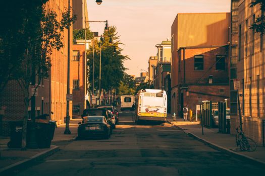 Vibrant city street view with a bus and cars under warm sunset lighting in Boston.