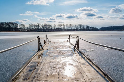 A serene winter scene with a frozen pier leading into a tranquil lake, surrounded by frosty nature.