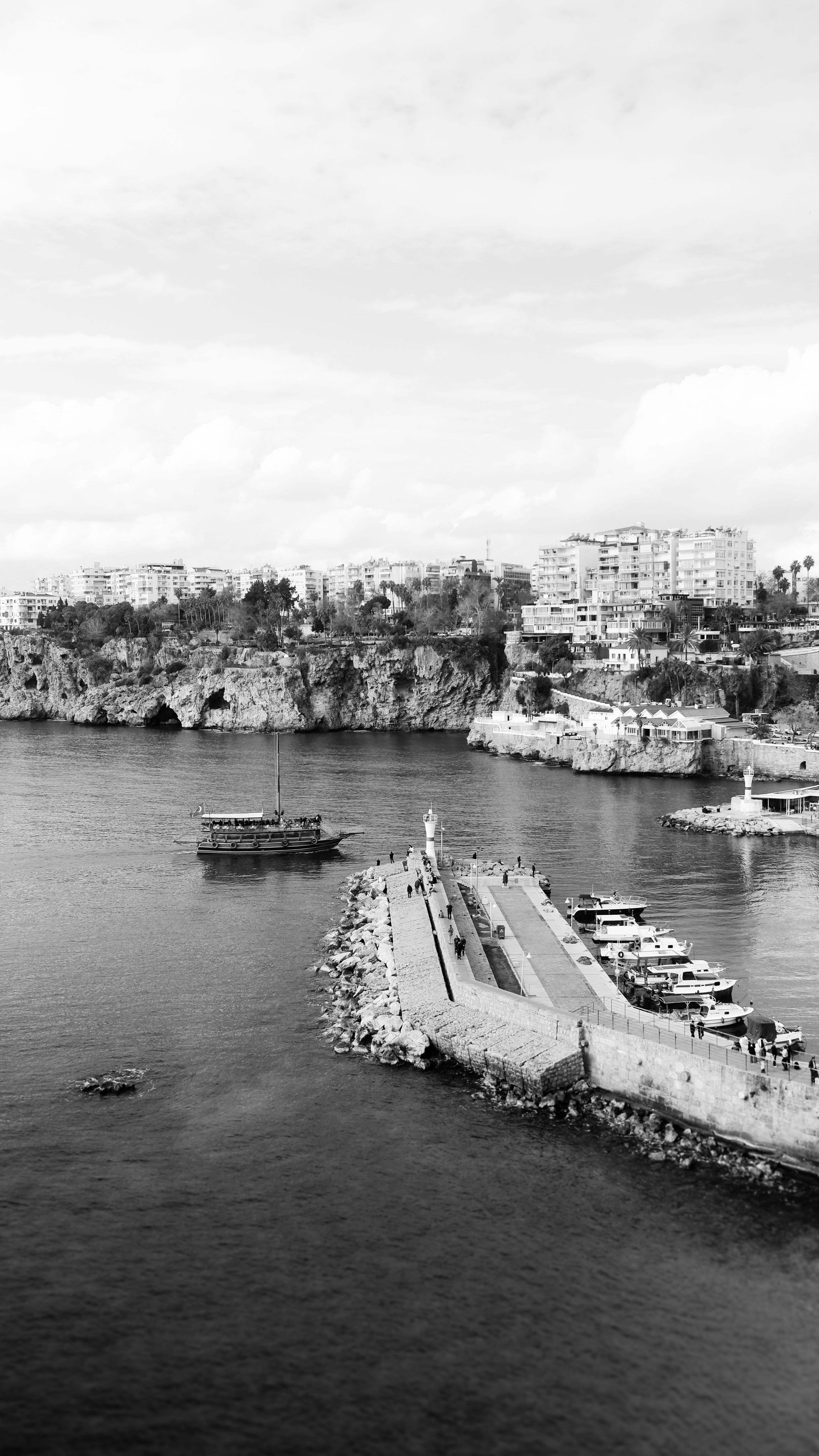 Scenic black and white aerial view of a city pier with boats and coastline in the background.