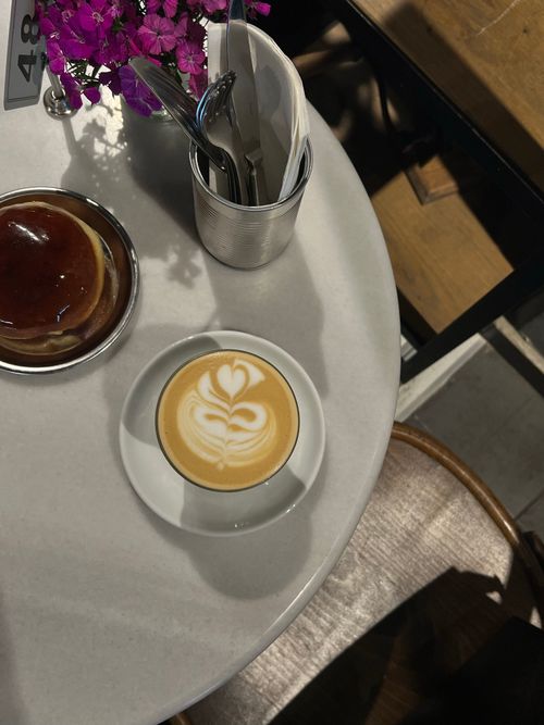Free Top view of latte with art and pastry on a round cafe table with flowers. Stock Photo