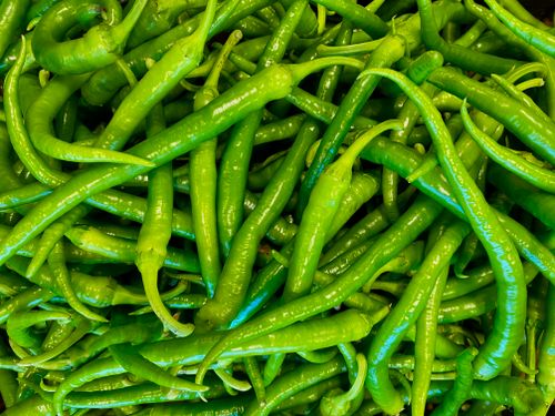 Free A vibrant heap of fresh green chilies, perfect for cooking or market scenes. Stock Photo