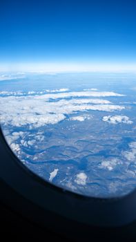Breathtaking aerial view of clouds and landscape from an airplane window.