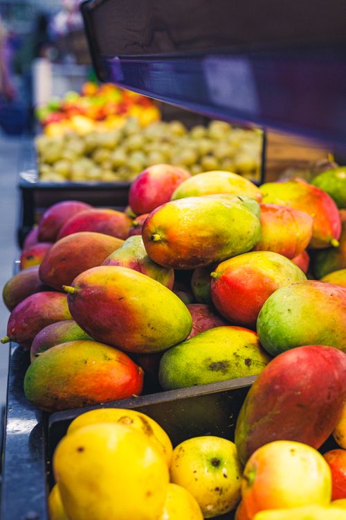 Free Colorful mangoes on display at a bustling market stall. Stock Photo