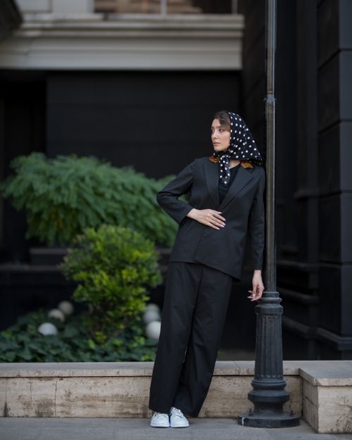 Free Woman in elegant black attire poses by lamp post in urban setting. Stock Photo