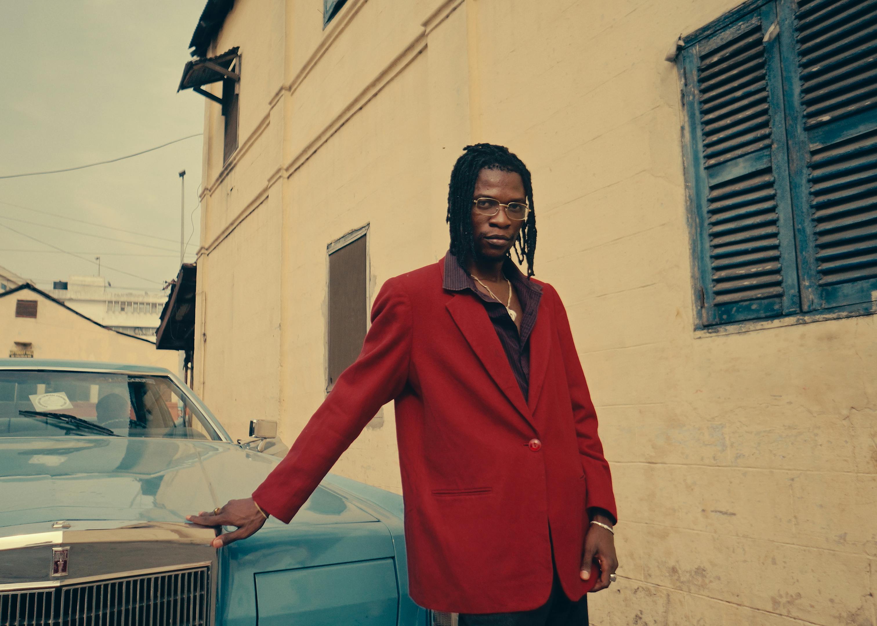 fashionable man in red blazer by a classic car