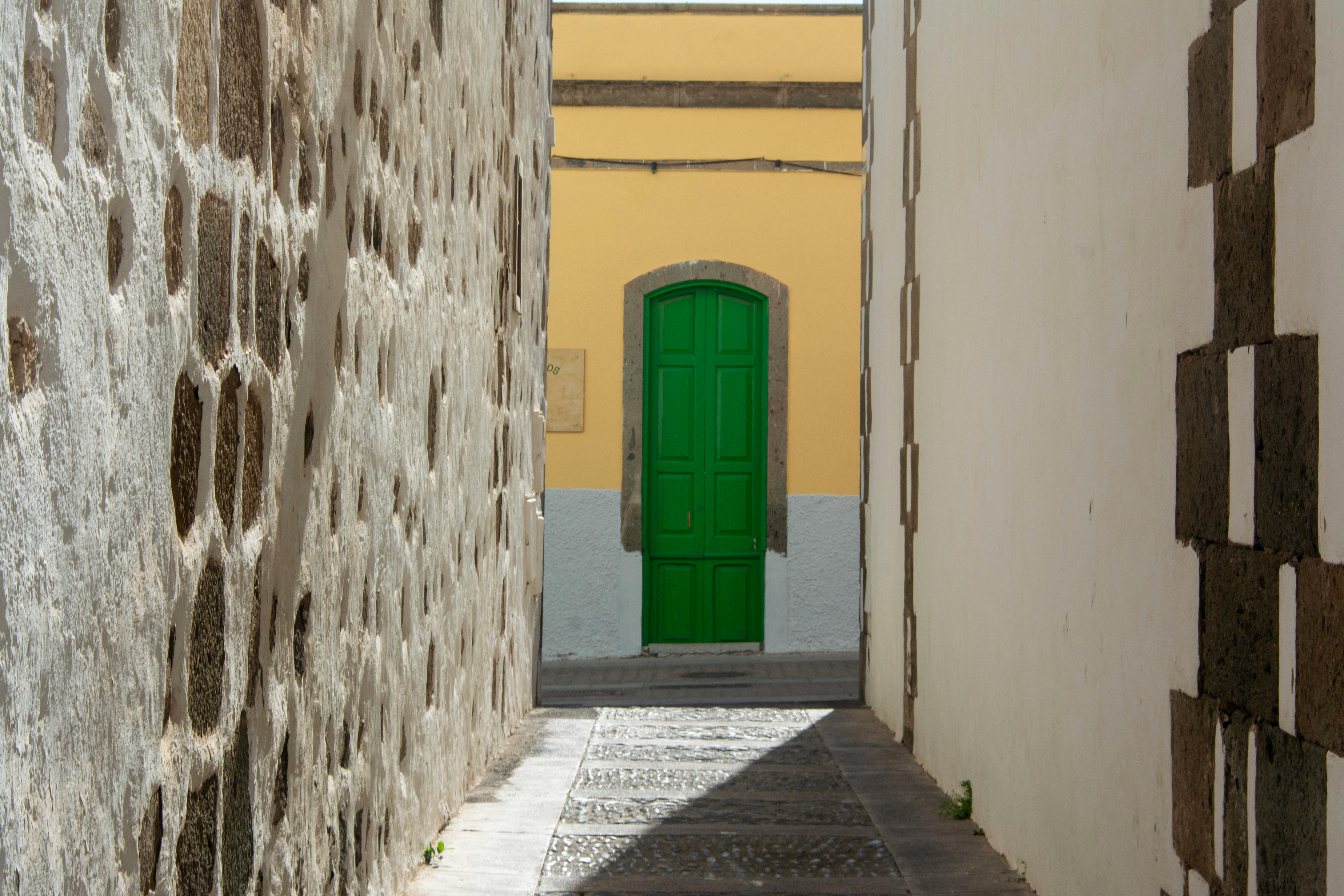 gratis Een pittoresk steegje in Agüimes, Spanje, met een felgroene deur, omlijst door historische stenen muren. Stockfoto