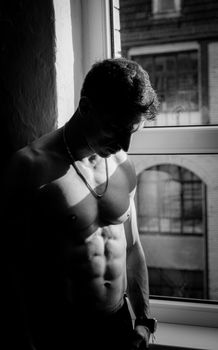 Black and white portrait of a muscular man in Berlin, highlighting light and shadow.