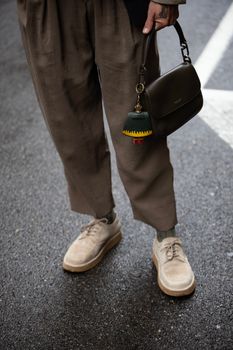 Chic streetwear fashion in Milan featuring brown trousers and suede shoes.