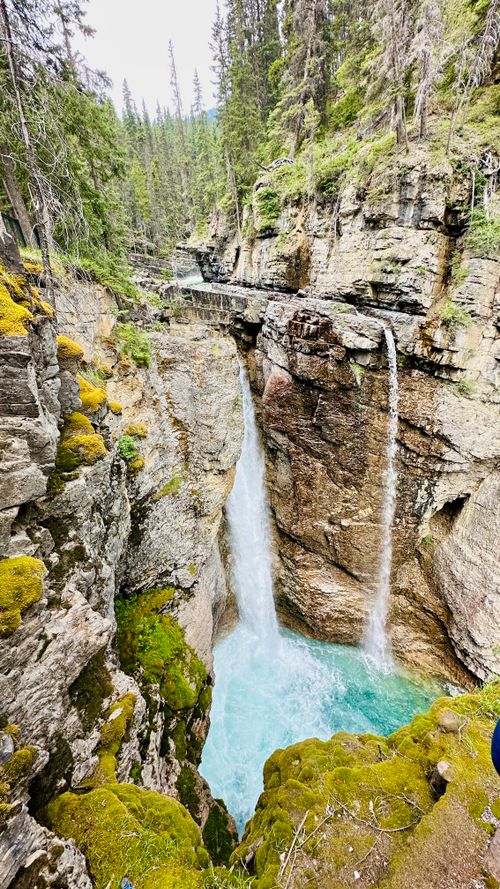 Free Beautiful waterfall cascading in a mossy canyon surrounded by lush forest. Stock Photo