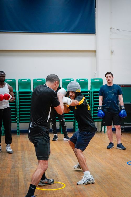 Free Group boxing training session with athletes sparring in an indoor gym setting. Stock Photo
