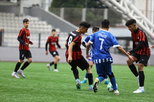 Teenage boys play competitive soccer outdoors. Intense match on green field.