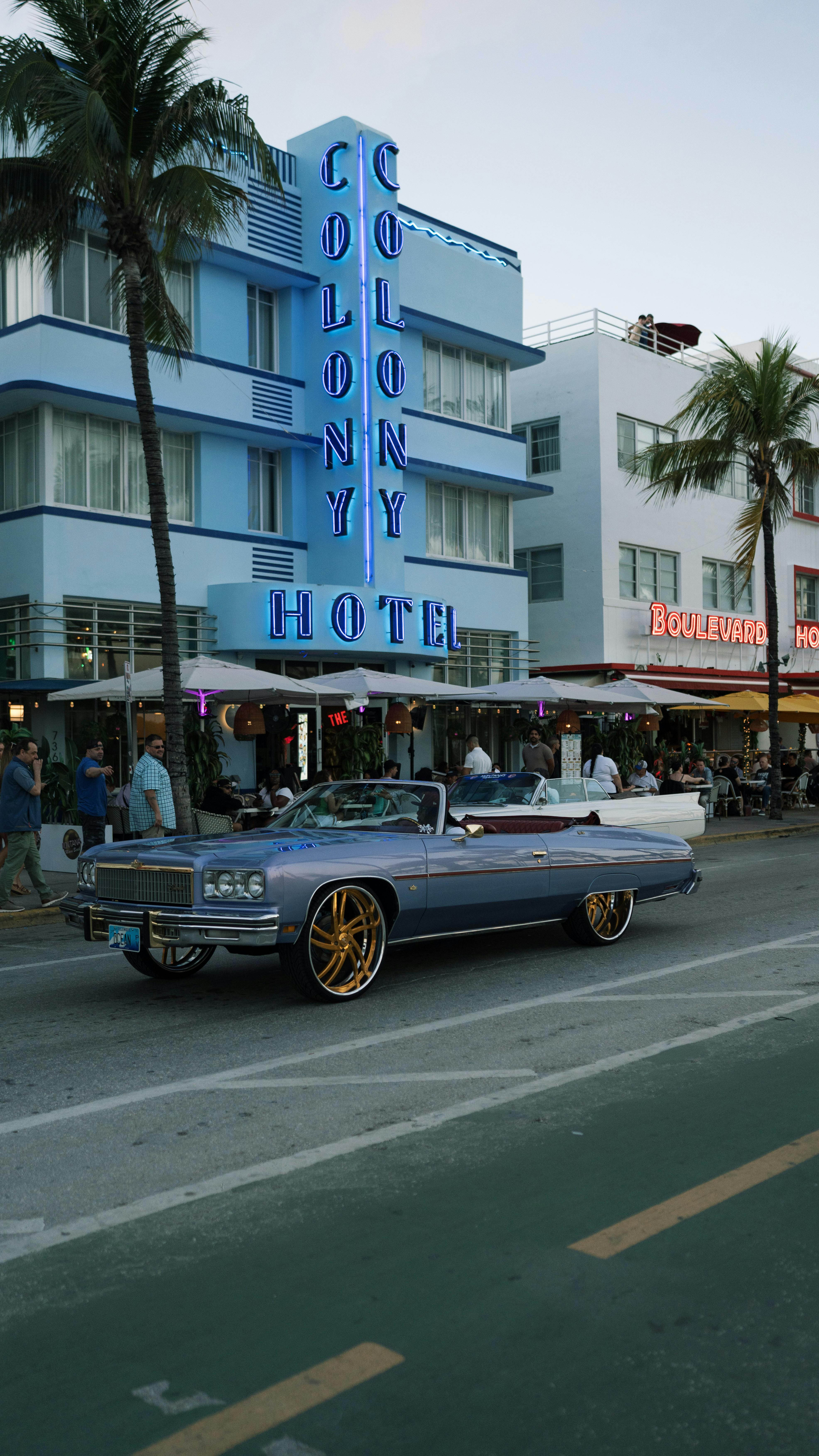 Stylish vintage car parked near iconic Colony Hotel on Ocean Drive, Miami Beach.