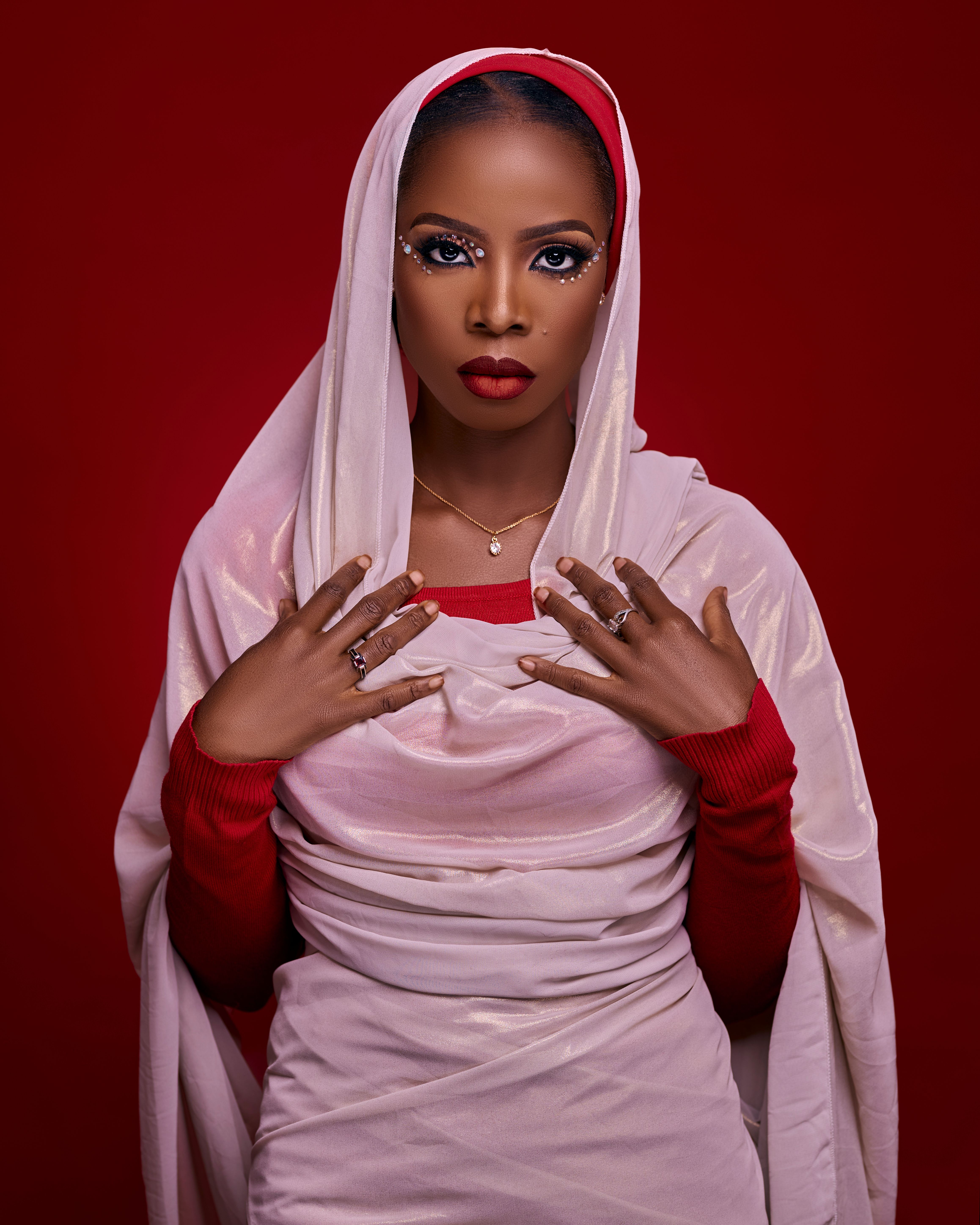 Portrait of an elegant woman wearing traditional attire with striking makeup against a red background.