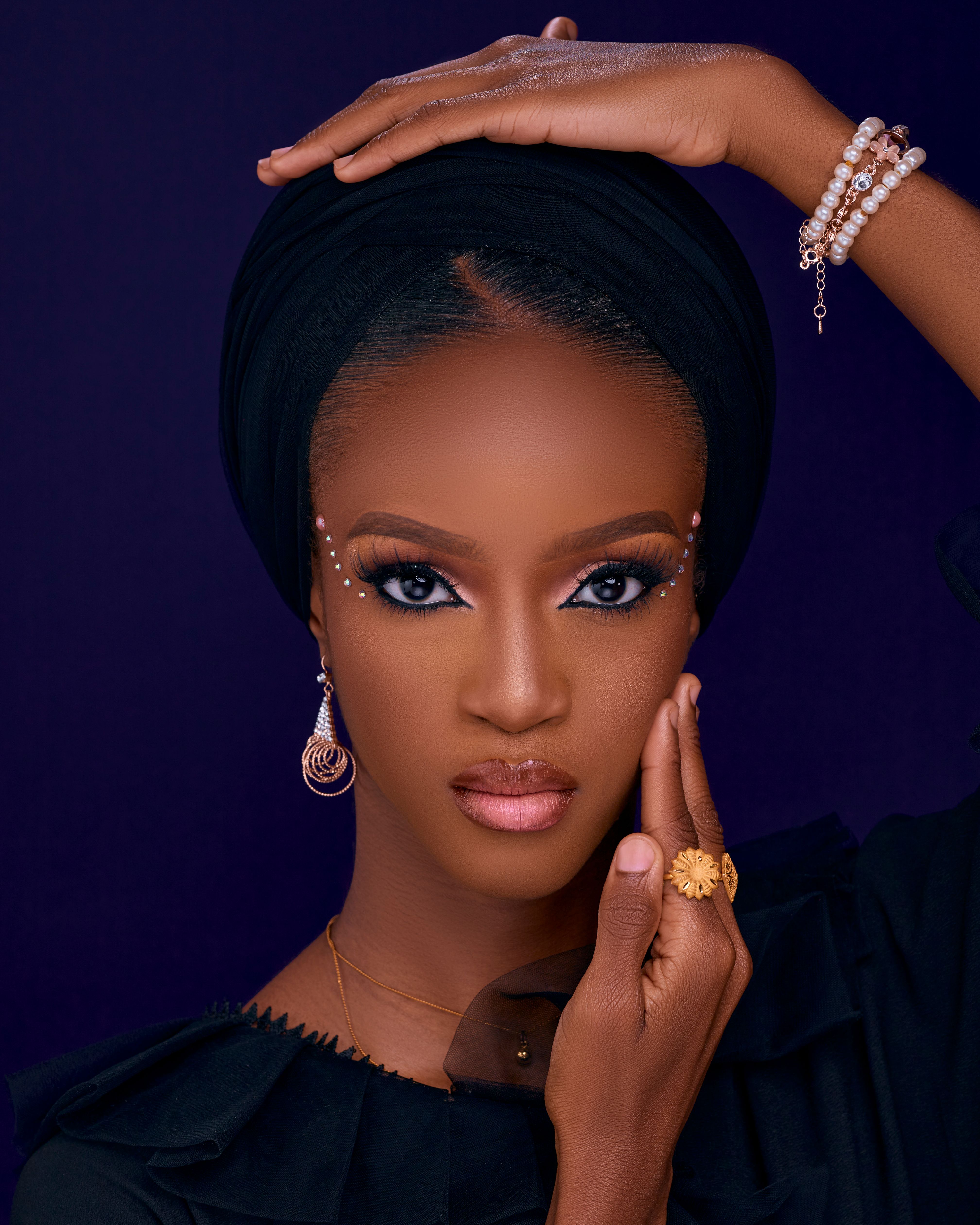 Stunning portrait of a woman wearing elegant jewelry and makeup against a dark background.
