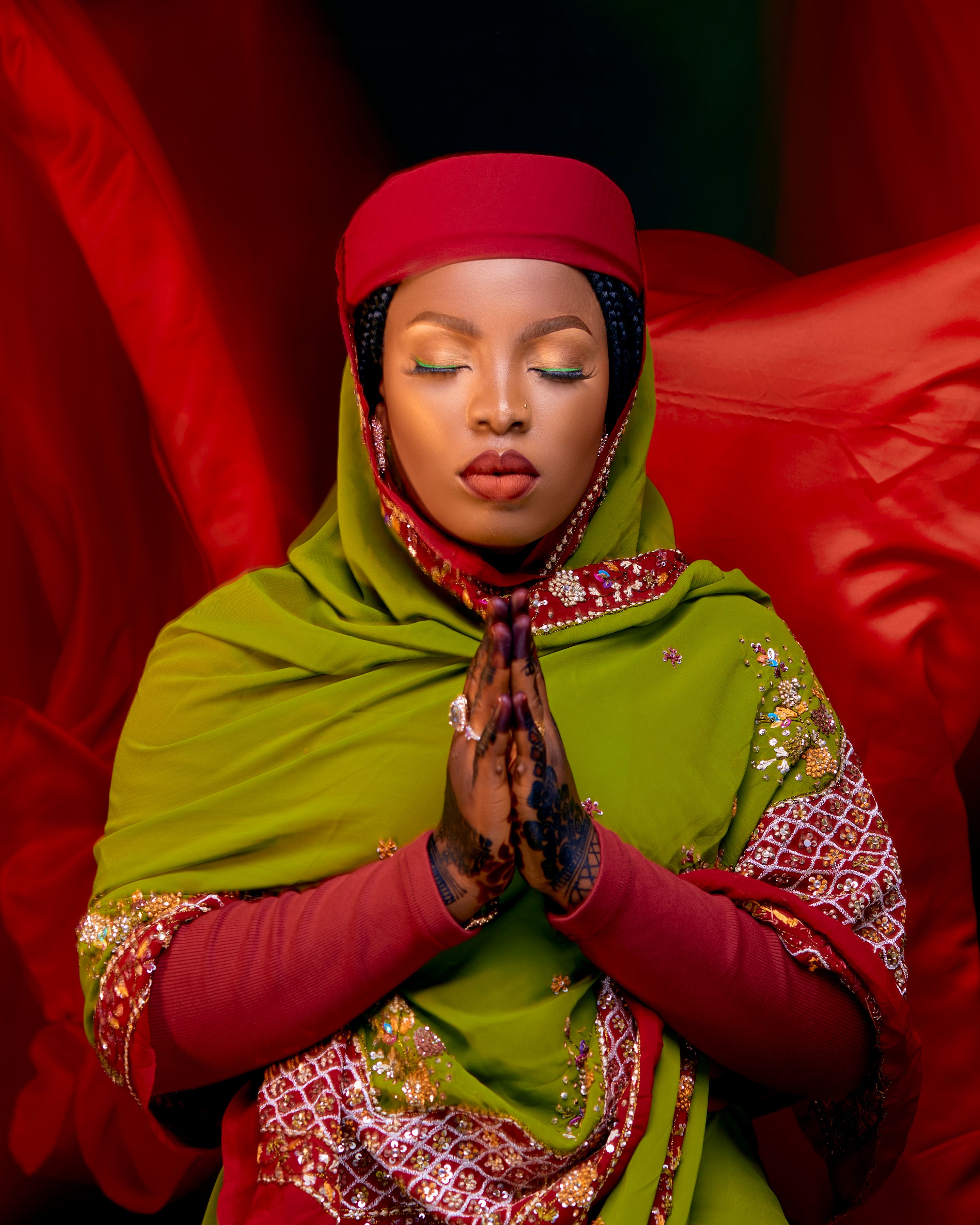 A woman in vibrant traditional clothing meditates with eyes closed, exuding calm and elegance.