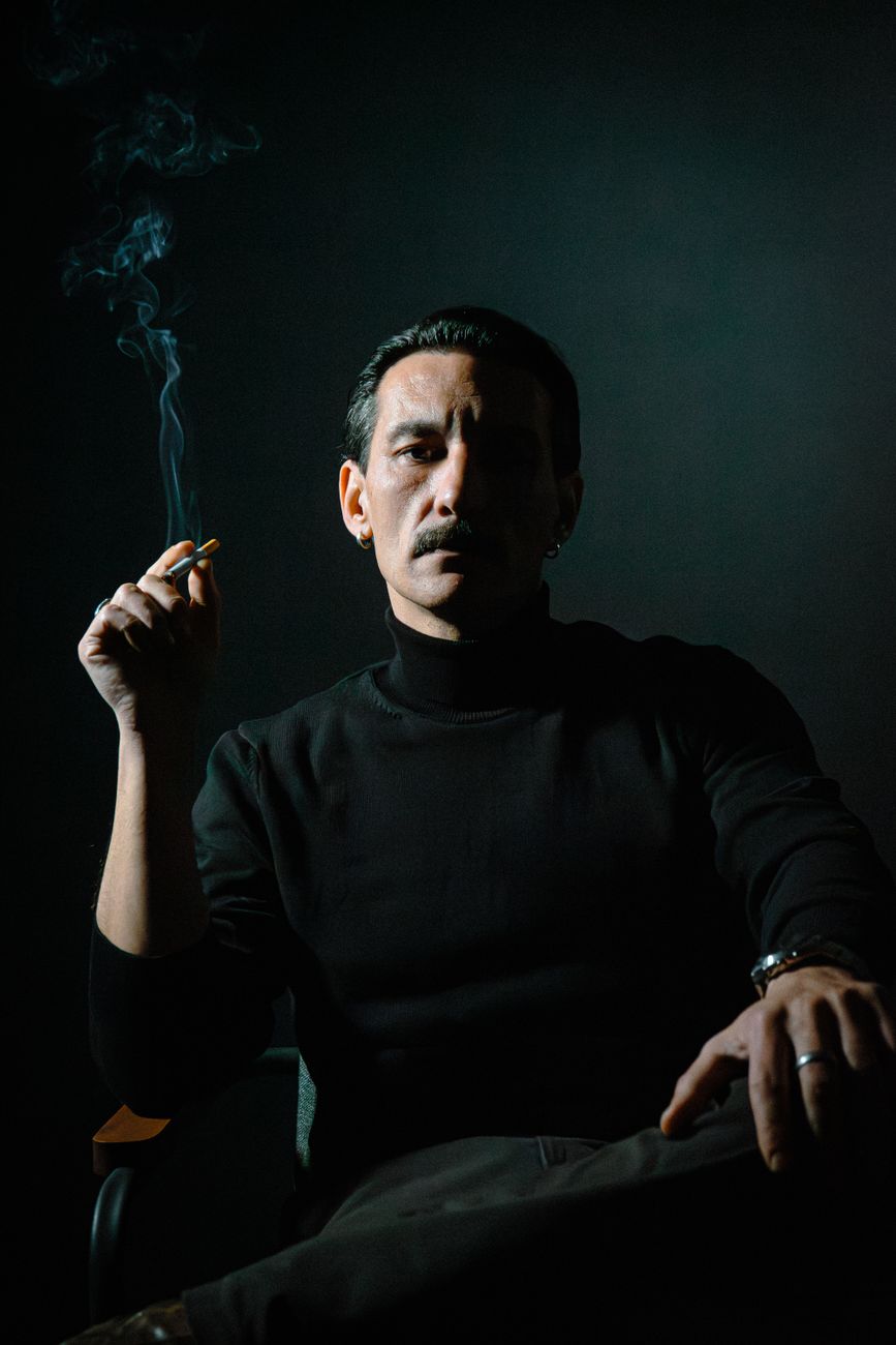 Intense portrait of a man smoking in dramatic low lighting, creating a mysterious atmosphere.