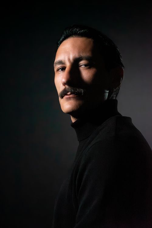 Free Dramatic portrait of a man with a mustache in low lighting, creating a moody atmosphere. Stock Photo