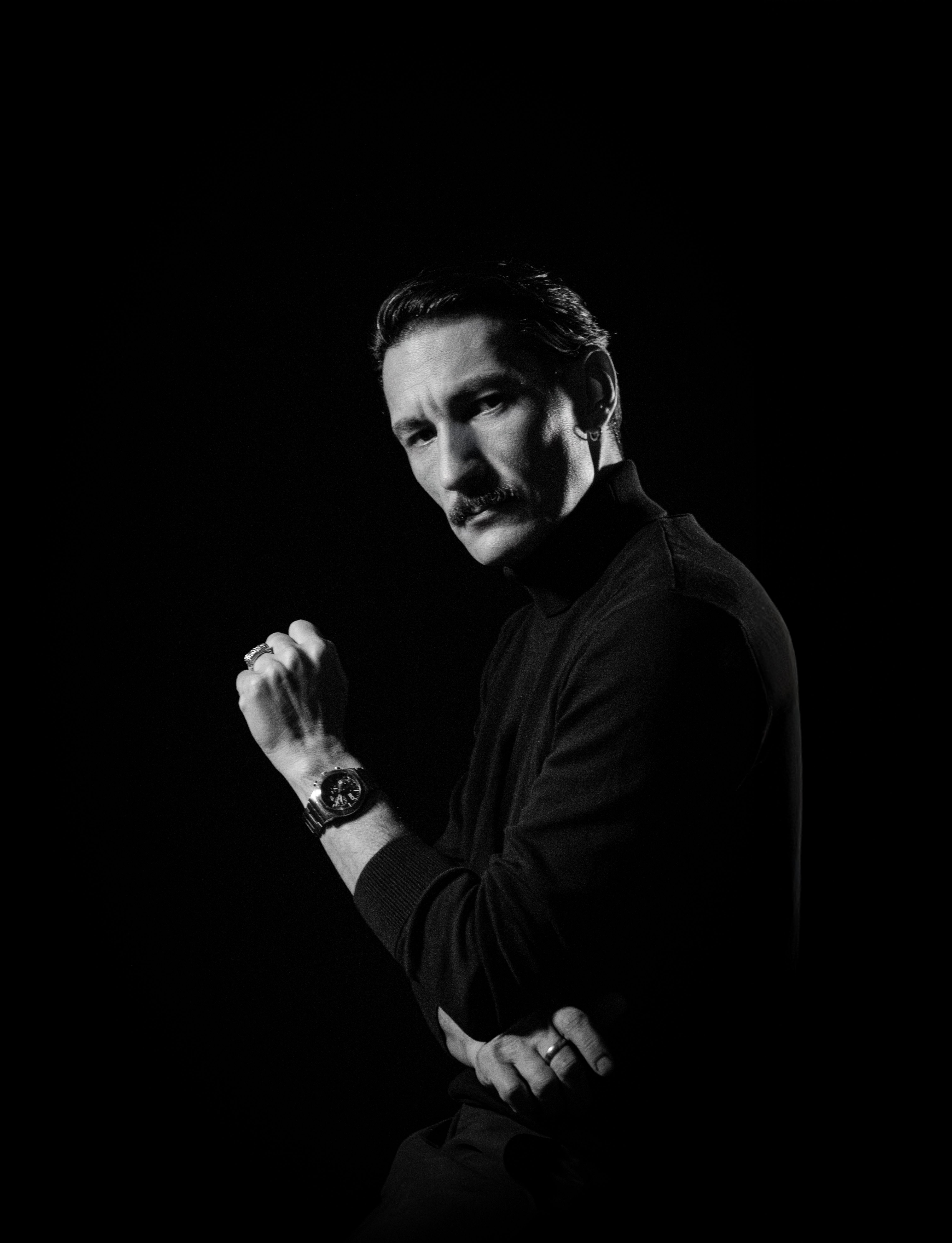Sophisticated black and white portrait of a man wearing a watch, exuding elegance.