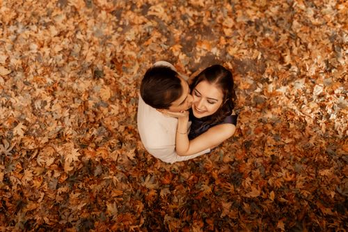 Free A loving couple embraces amidst fallen autumn leaves, viewed from above. Stock Photo